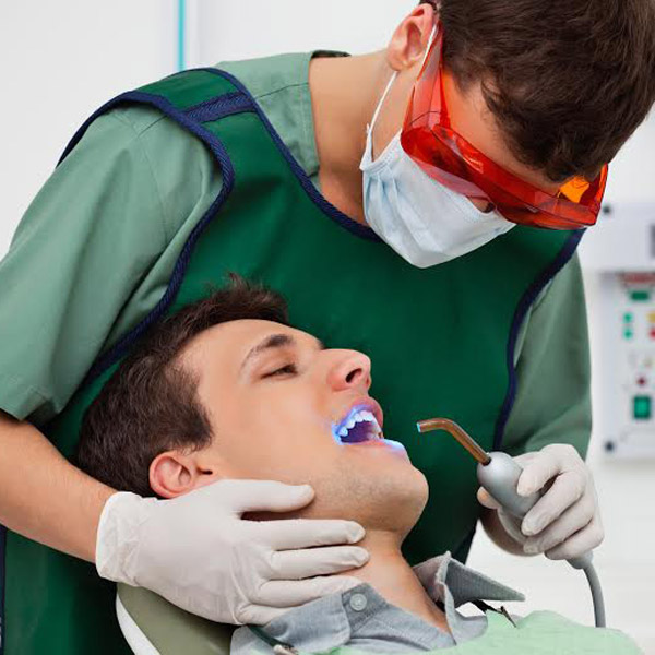 Dentist using UV light on patients teeth